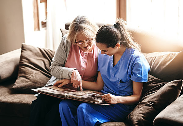 Shot of a nurse and a senior woman looking at a photo album together