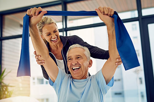 Shot of a physiotherapist helping a senior patient stretch with a stretch band in her office